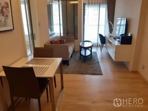 公寓 出租在Watthana, Bangkok - 开放式客餐厅，配沙发、电视柜、书桌并连接阳台门。