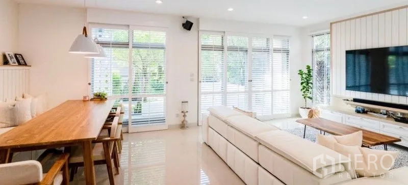 独立式住宅 出租 - 明亮的客餐一体空间，长木桌、白色沙发和大面积窗户百叶。