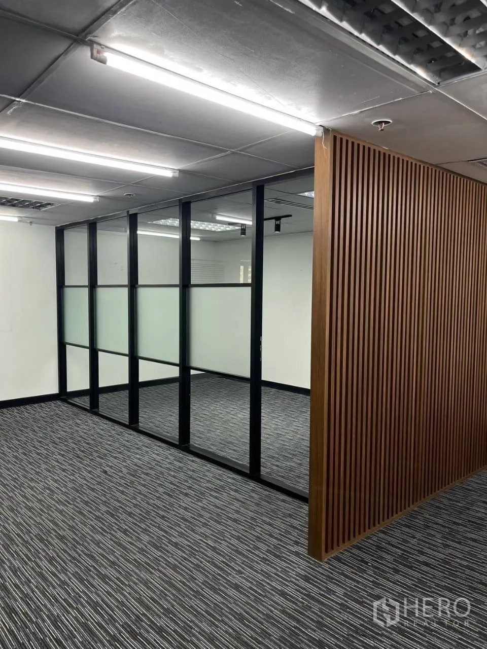 Office Space for rent in Khlong Toei, Bangkok - Frosted glass partition wall with black frames beside a wooden slat divider.