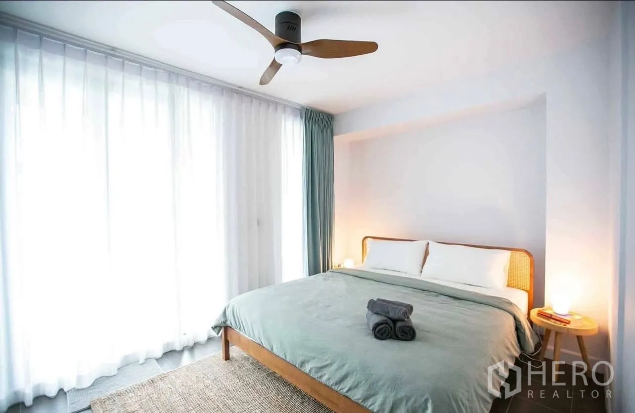Townhouse for rent in Suan Luang, Bangkok - Bedroom with king bed, ceiling fan, soft lighting and sheer curtains.