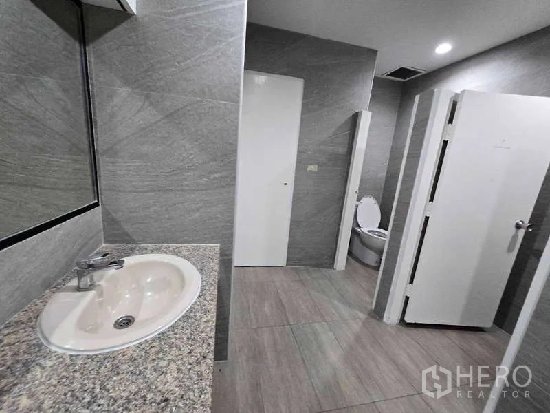 Office Space for rent in Khlong Toei, Bangkok - Restroom stalls with white doors and granite countertop sink.