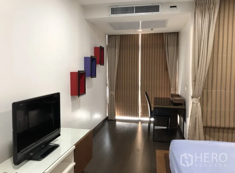 คอนโด ให้เช่าในKhlong Toei, Bangkok - ห้องนอนพร้อมชั้นวางทีวี โต๊ะทำงานริมหน้าต่าง และผ้าม่านทึบแสง