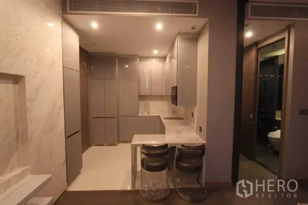 คอนโด ให้เช่าในHuai Khwang, Bangkok - ครัวแบบเปิดพร้อมเคาน์เตอร์บาร์และสตูลสองตัวติดกับพื้นที่นั่งเล่น