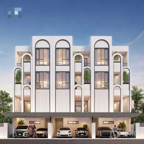 Townhouse for sale - Modern 3.5-storey townhouse façade with arched windows, balconies, greenery and covered parking at dusk.