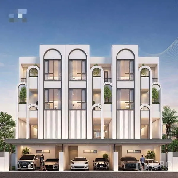 Townhouse for sale - Modern 3.5-storey townhouse façade with arched windows, balconies, greenery and covered parking at dusk.