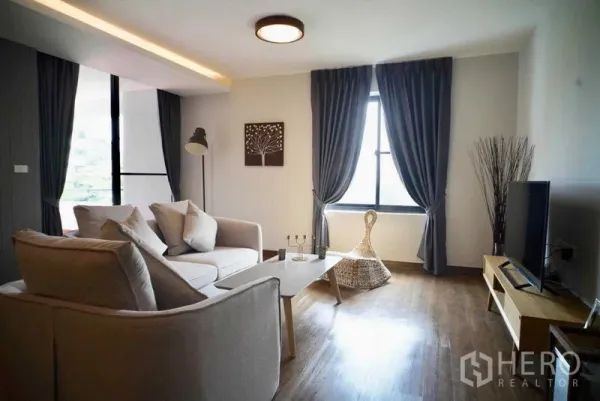 Condominium for rent in Watthana, Bangkok - Cozy lounge with sofa set, TV console and a large curtained window.