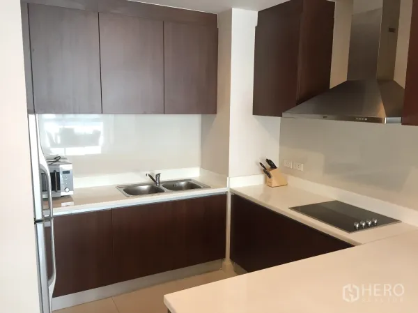 คอนโด ให้เช่าในPathum Wan, Bangkok - ห้องครัวรูปตัว U ตู้ไม้สีเข้ม เคาน์เตอร์สีขาว อ่างล้างจานคู่ เตาไฟฟ้าและเครื่องดูดควัน