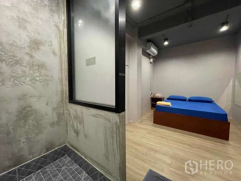 店屋 出租在Lat Phrao, Bangkok - 简约卧室，蓝色床品，木地板，旁连水泥风淋浴间。