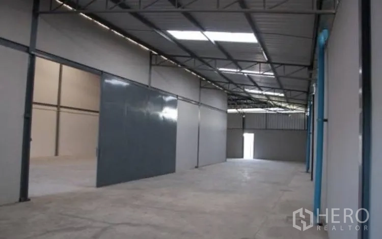 Warehouse for rent in Bang Phli, Samut Prakan - Open warehouse aisle with sliding door and roof structure allowing natural light.