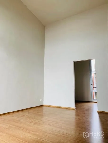 Home Office for rent - Large room with very high ceiling and doorway leading to another bright space.