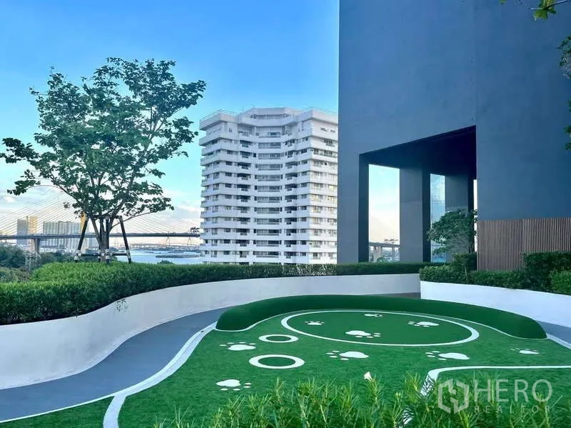 Condominium for rent or sale in Bangkok - Landscaped outdoor pet lawn with city and river backdrop at Canapaya Residences.