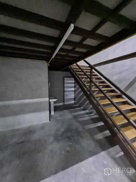 Warehouse for rent in Prawet, Bangkok - Ground-floor area with steel staircase, a sink, and access door beneath the mezzanine.
