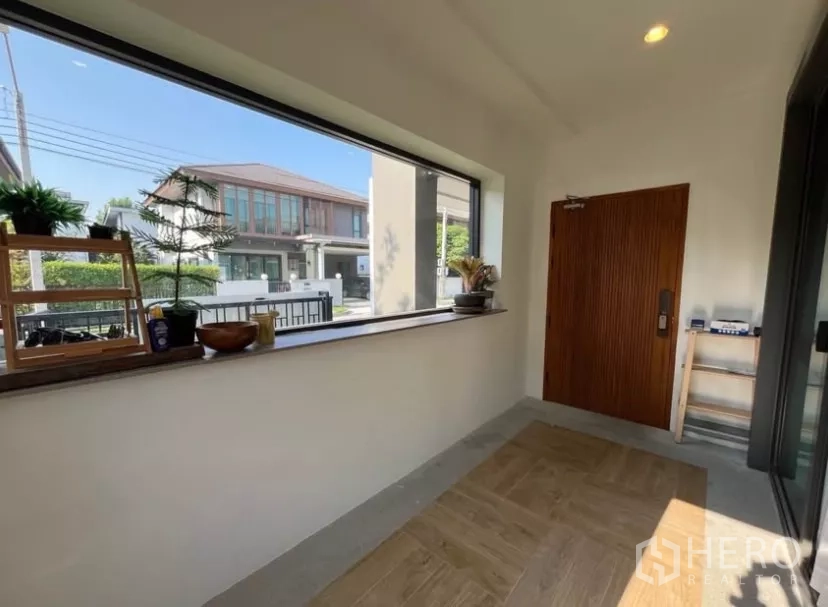 Detached House for rent in Prawet, Bangkok - Entrance foyer with a long picture window, wooden front door and storage shelf.