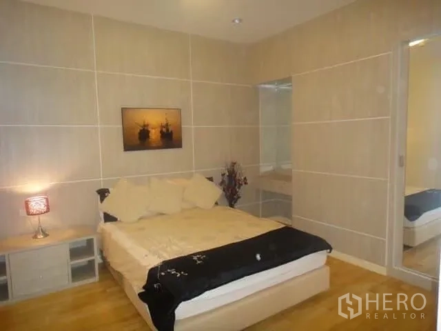 คอนโด ให้เช่าในKhlong San, Bangkok - ห้องนอนที่สองผนังโทนกลาง โต๊ะข้างเตียง และประตูเชื่อมพื้นที่ห้องน้ำ