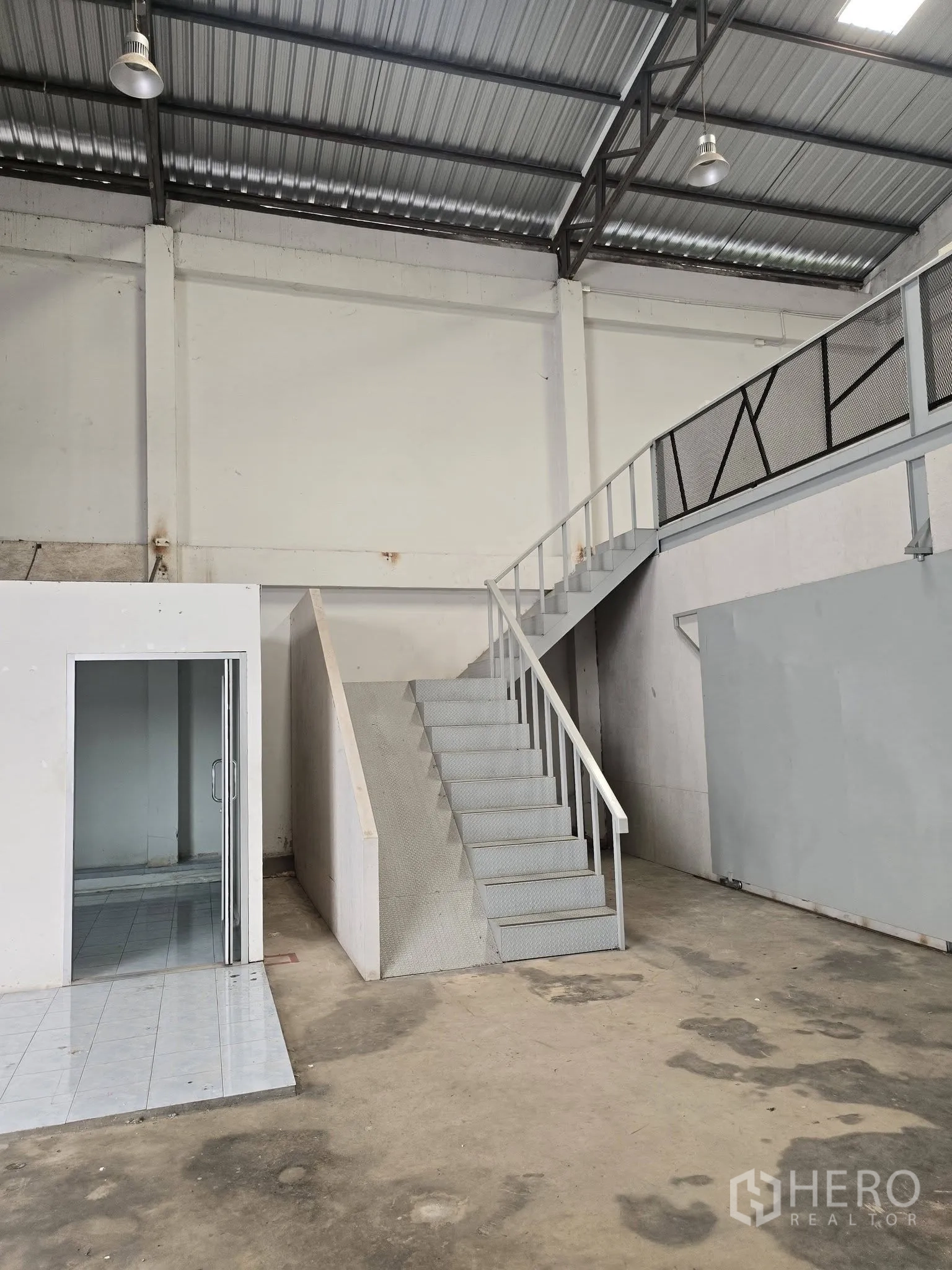 Warehouse for rent in Bang Na, Bangkok - Staircase leading to the mezzanine beside the internal office, with high ceiling and pendant industrial lights.