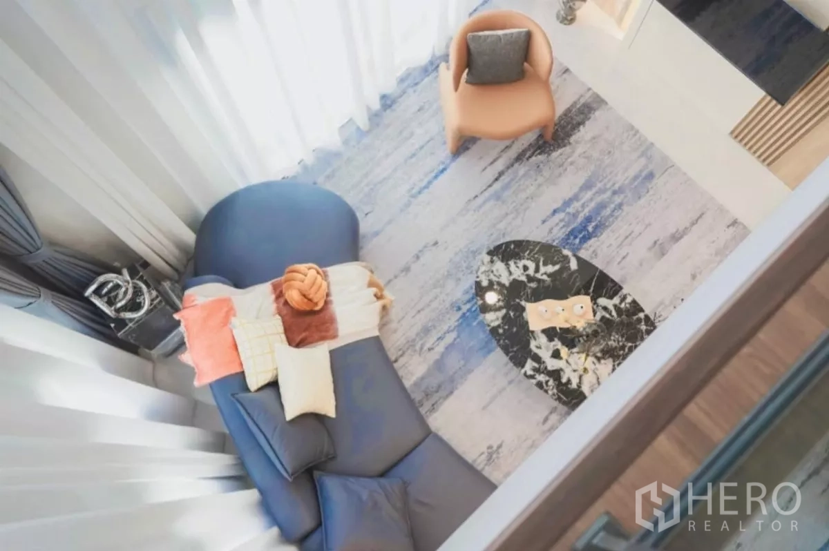 独立式住宅 出租在Bang Phli, Samut Prakan - 俯瞰挑高客厅，可见弧形沙发、单椅与花纹地毯。