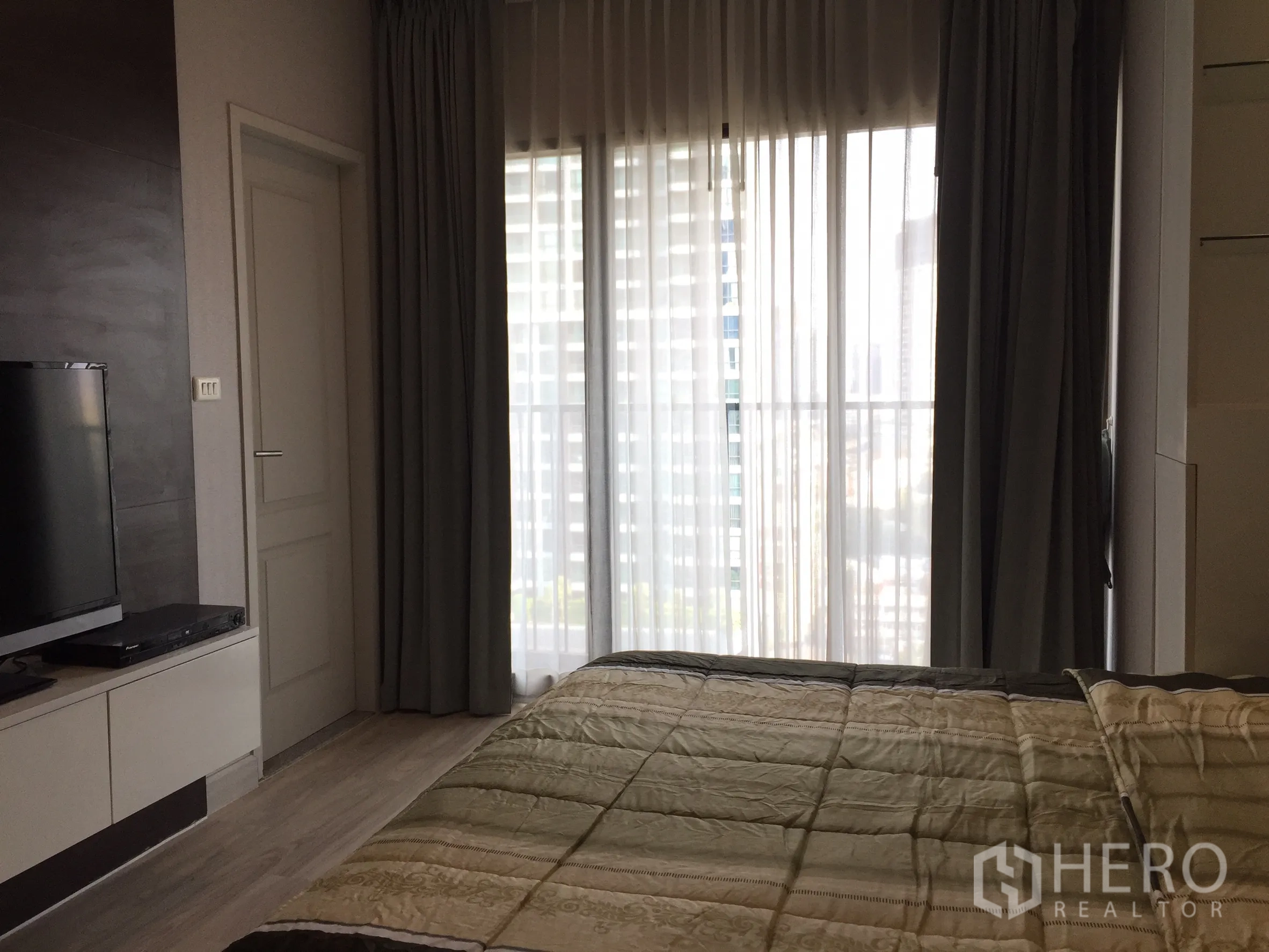 คอนโด ให้เช่าหรือขายในBangkok - ห้องนอนมีผ้าม่านโปร่งถึงพื้น เปิดสู่ระเบียงและวิวเมือง