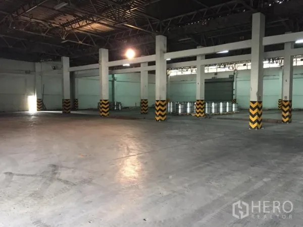 คลังสินค้า ให้เช่าในPathum Thani - ภายในโกดังโปร่ง เพดานโครงเหล็กสูง พื้นคอนกรีต และเสาติดแถบเตือนสีเหลืองดำ