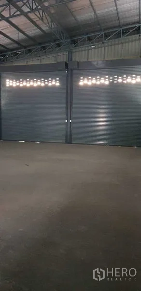 Warehouse for rent in Lat Lum Kaeo, Pathum Thani - Two oversized roller shutter doors along the warehouse wall.