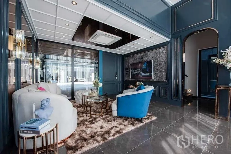 独立式住宅 出售在Prawet, Bangkok - 深蓝墙板与大理石地面的客厅，豪华沙发与嵌入式电视背景墙。