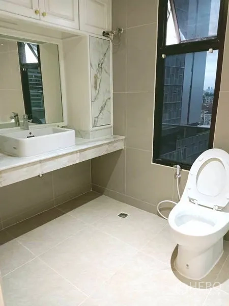 Condominium for  in Watthana, Bangkok - Bathroom with vanity, mirror and window overlooking skyline.