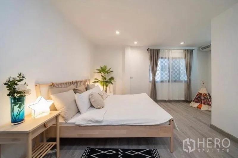 Detached House for rent in Ratchathewi, Bangkok - Spacious bedroom with large windows, light wood bed and soft lighting.