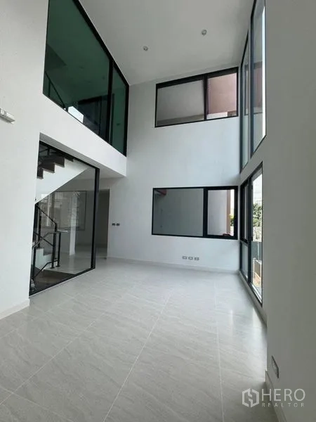 Townhouse for rent - Sunlit double-volume lounge featuring floor-to-ceiling corner windows.