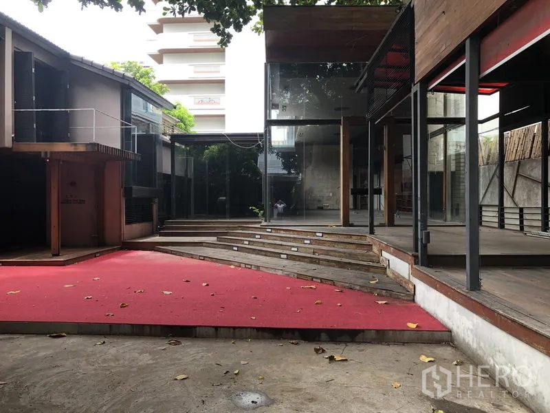 零售空间 出租在Bang Khae, Bangkok - 中央庭院设红毯平台、台阶与玻璃立面的建筑。