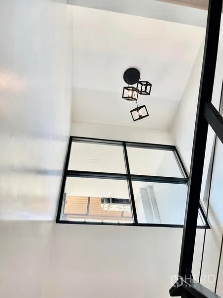 Townhouse for rent in Khlong Toei, Bangkok - Double-height stairwell ceiling with cube pendant lights and interior window.