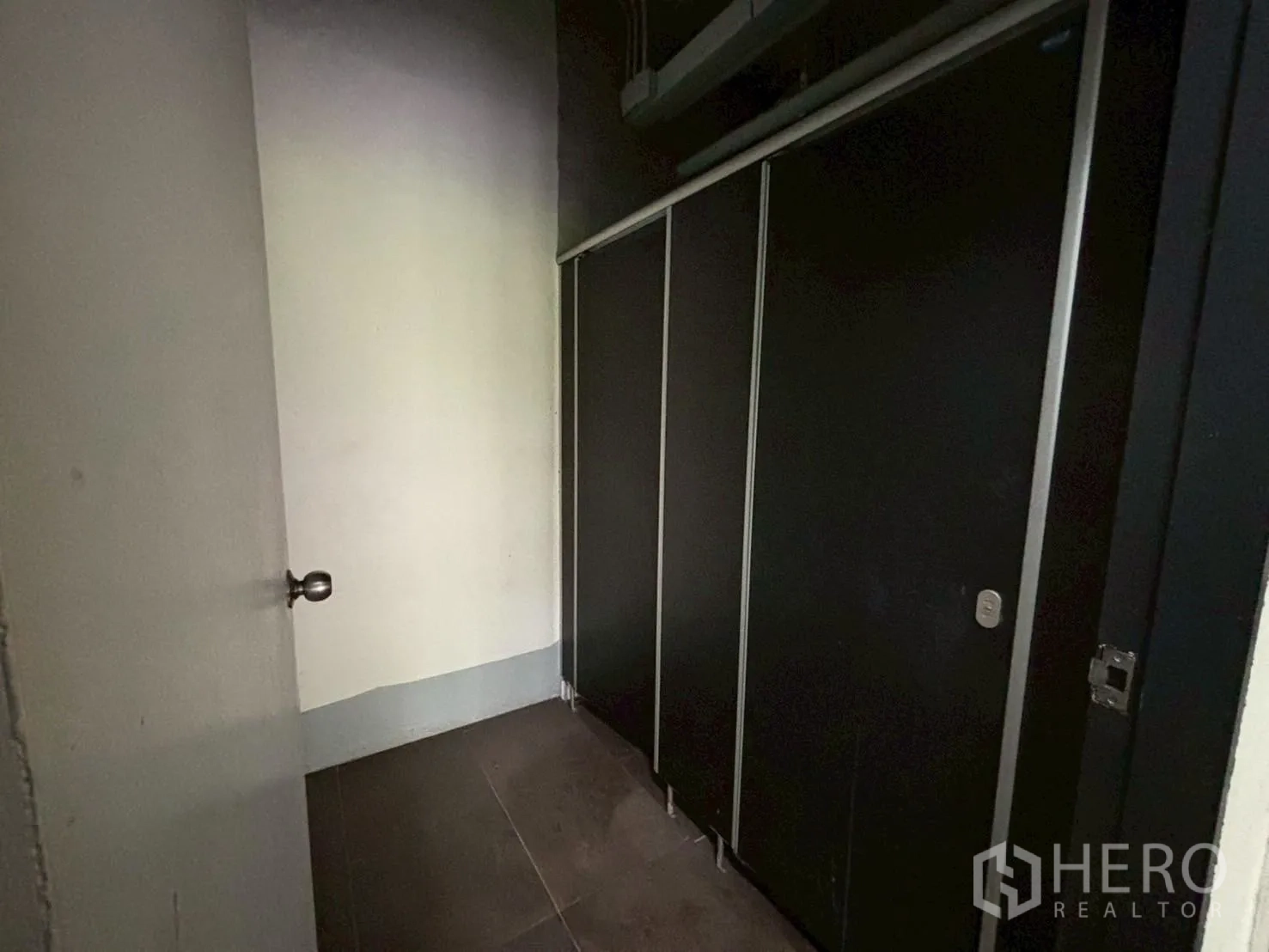 สำนักงาน ให้เช่า - โถงห้องน้ำพร้อมฉากกั้นส้วมสีดำและพื้นกระเบื้อง.