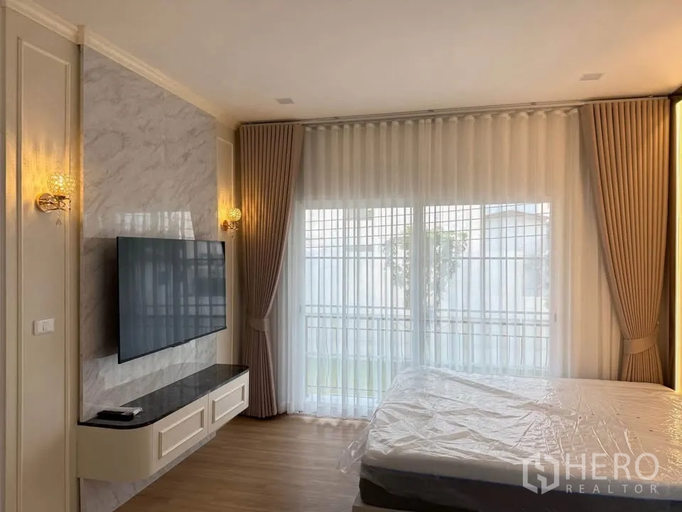 บ้านแฝด for rent in Mueang Samut Prakan, Samut Prakan - ห้องนอนพร้อมทีวีติดผนัง ผนังตกแต่งลายหินอ่อน และม่านโปร่ง