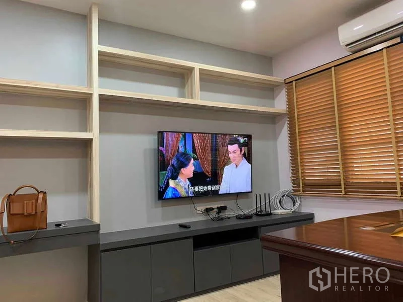 Townhouse for rent - Custom media wall with floating cabinets and a wall-mounted TV beside timber window blinds.