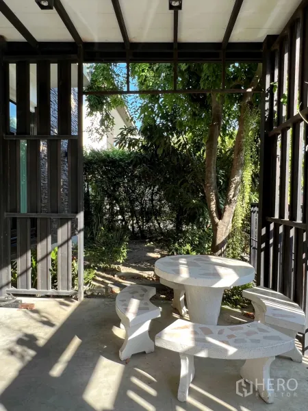 Detached House for rent in Prawet, Bangkok - Shaded patio under a pergola with round stone table set overlooking a leafy garden.
