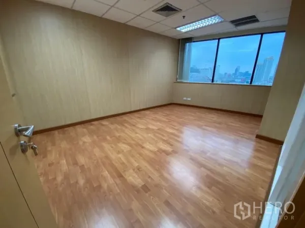 Office Space for rent in Watthana, Bangkok - Empty office room with wood flooring, drop ceiling, and a large window showing Bangkok skyline views.