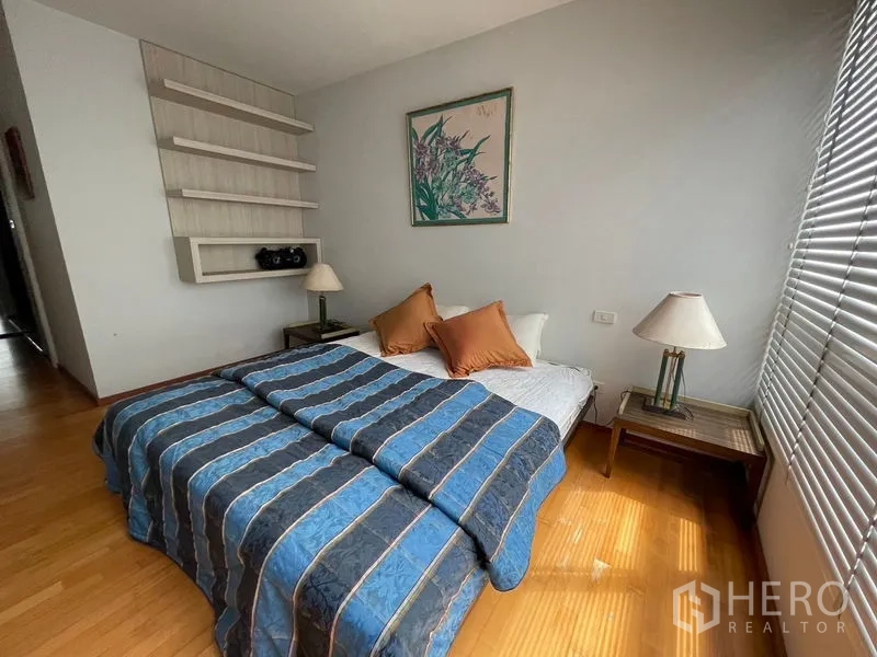 คอนโด ขายในKhlong Toei, Bangkok - ห้องนอนอบอุ่น เตียงคู่ โต๊ะหัวเตียง และชั้นวางผนัง ข้างหน้าต่างบานเกล็ดยาว