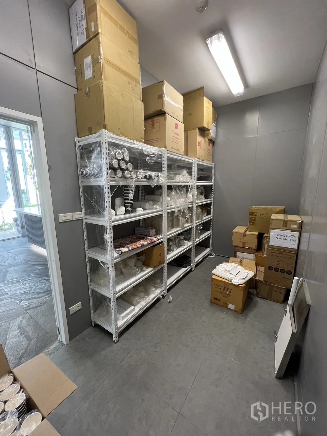 零售空间 出租在Khlong Toei, Bangkok - 后场储物间，配金属置物架与地砖地面。