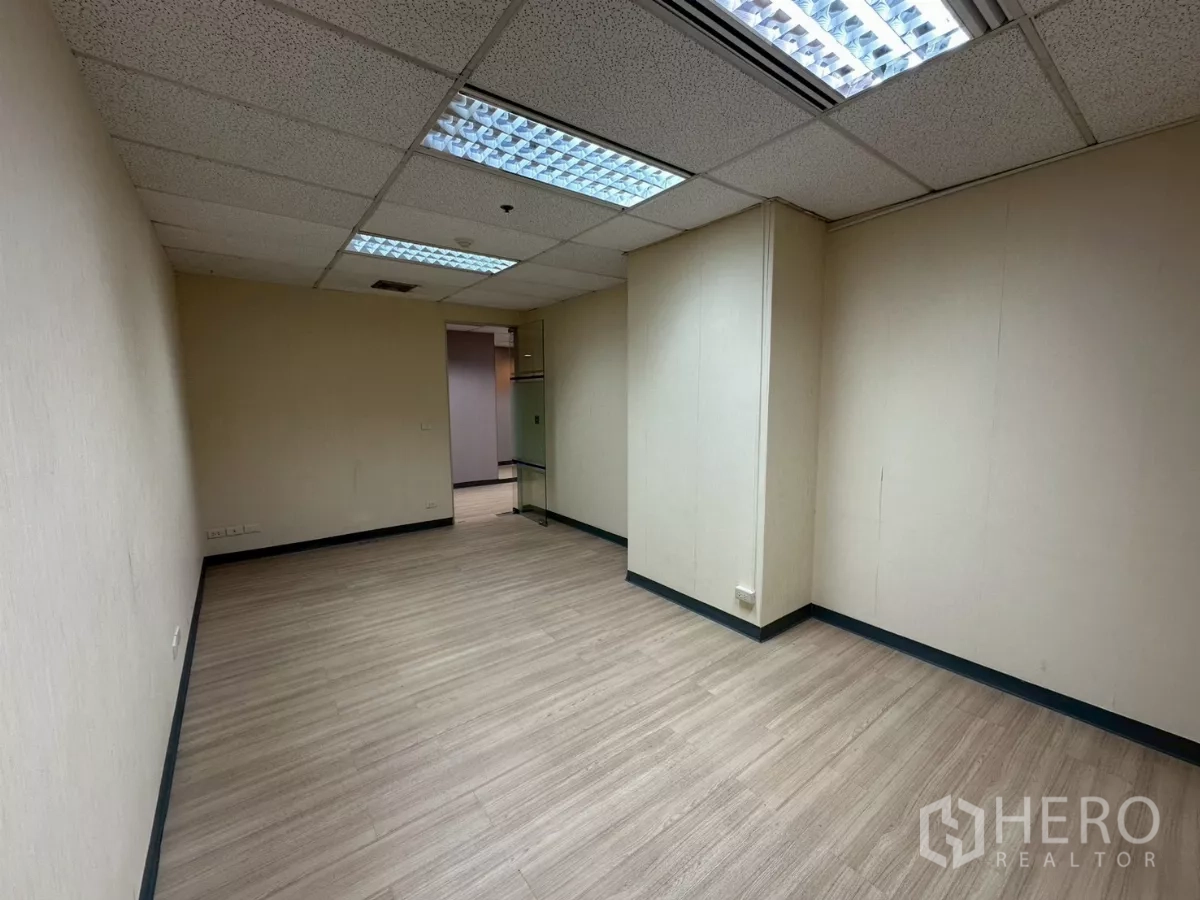 Office Space for rent in Watthana, Bangkok - Small office with light walls, wood‑look floor and fluorescent ceiling lights.