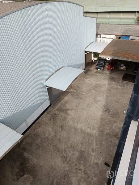工厂 出售在Ban Phaeo, Samut Sakhon - 俯视金属夹芯板仓库旁的侧院，设装卸雨棚与停车位