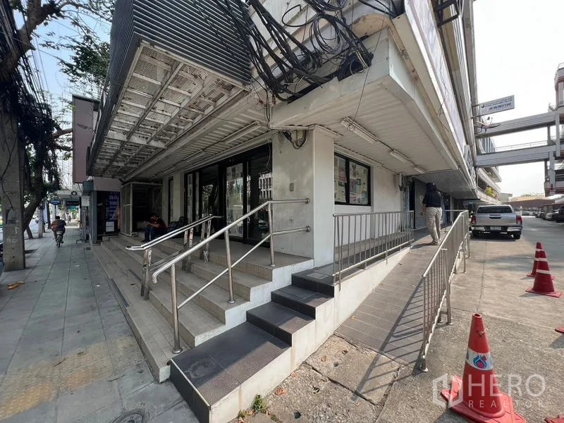 Shophouse for rent in Watthana, Bangkok - Corner exterior of the shophouse with sidewalk, steps and accessibility ramp.