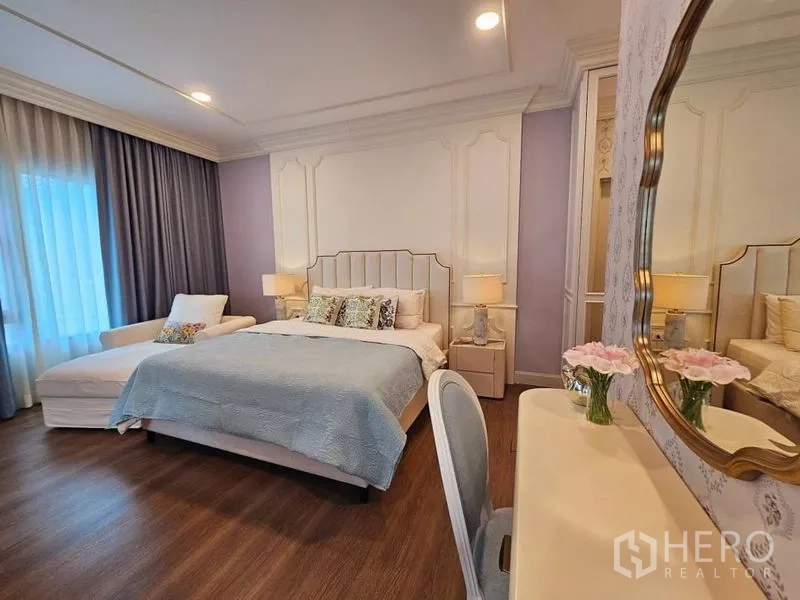 Detached House for rent or sale in Saphan Sung, Bangkok - Spacious bedroom with upholstered bed, chaise lounge, warm lighting and full-length curtains.
