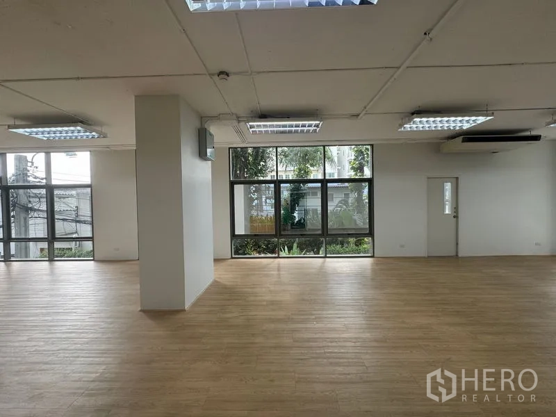 Office Space for rent in Sathon, Bangkok - Wide workspace with wood‑look flooring, multiple ceiling lights and greenery outlook.