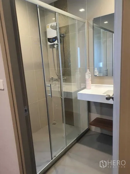 Condominium for rent - Bathroom with glass-enclosed shower, water heater and wide vanity with mirror.