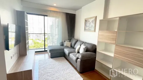 Condominium for rent in Watthana, Bangkok - Living area opening to a balcony via sliding glass doors with skyline views.
