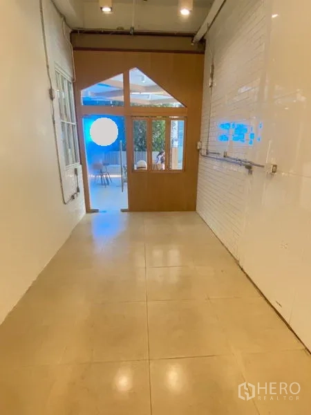 พื้นที่ขายปลีก ให้เช่าในWatthana, Bangkok - ภายในร้านรูปทรงยาว พื้นกระเบื้อง เดินสู่ประตูและหน้าต่างกรอบไม้ พร้อมผนังอิฐขาว.