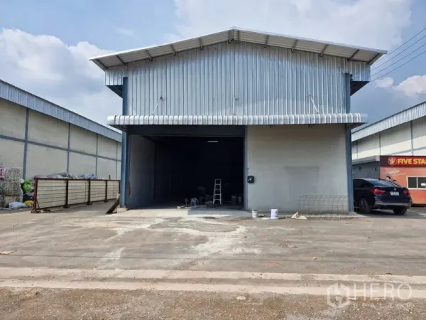 Warehouse for rent in Bang Khun Thian, Bangkok - Front view of warehouse bay with awning, roller door, and parking area in an industrial complex.