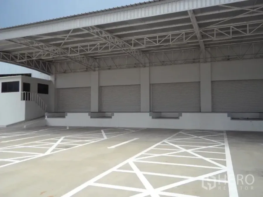 Warehouse for rent in Bang Sao Thong, Samut Prakan - Covered loading bays with multiple roller shutters and a raised dock platform.
