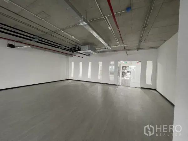 办公空间 出租在Bang Rak, Bangkok - 开放式办公区，面对玻璃入口与竖向采光窗，混凝土天花可见管道。