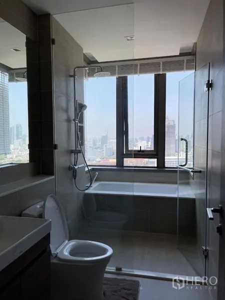 Condominium for rent in Bang Kho Laem, Bangkok - Bathroom with bathtub and rain shower beside a large window with city views.