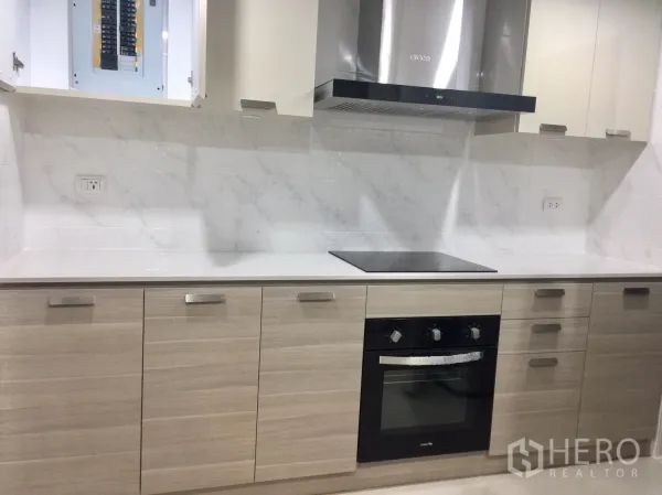 Condominium for rent in Pathum Wan, Bangkok - Sleek kitchen with marble splashback, built-in oven, induction cooktop and stainless range hood.