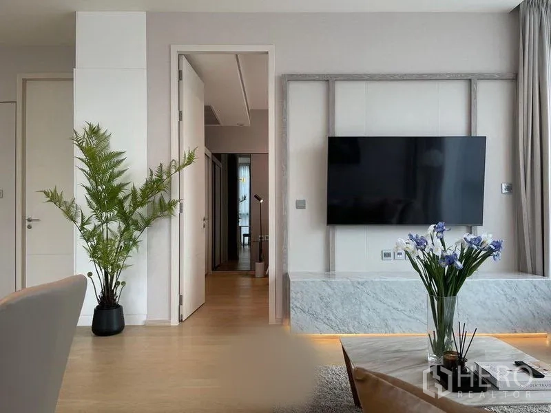 公寓 出租在Watthana, Bangkok - 起居区的大屏电视墙、绿植与茶几花艺点缀。